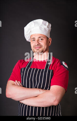 Hübscher Chef mit verschränkten Armen posieren vor schwarzem Hintergrund Stockfoto