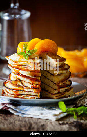 Stapel von hausgemachte Pfannkuchen mit pochierte Pfirsiche Stockfoto