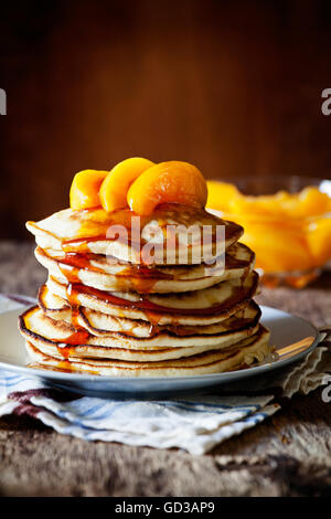 Stapel von hausgemachte Pfannkuchen mit pochierte Pfirsiche Stockfoto