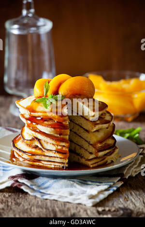 Stapel von hausgemachte Pfannkuchen mit pochierte Pfirsiche Stockfoto