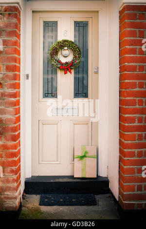 Weihnachtsschmuck. Ein Adventkranz mit einer roten Schleife an der Eingangstür eines Hauses. Stockfoto