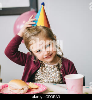 Ein junges Mädchen in einen Partyhut auf einer Geburtstagsfeier. Stockfoto