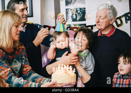 Eine Familie versammelt, um ein einjähriges Mädchen-Geburtstags-Party zu feiern. Ein Kuchen mit vielen Kerzen. Stockfoto