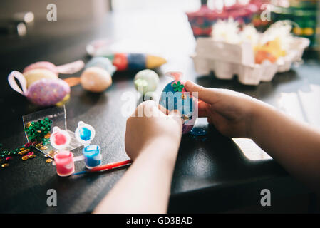 Ein Kind, Verzierung von Eiern zu Ostern mit Glitzer, Leim und Lack. Stockfoto