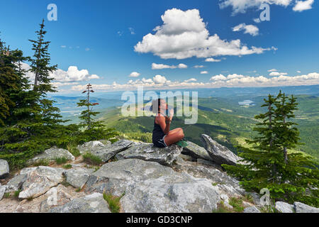 Frau sitzt auf dem Rand der Felsen, in einer Yoga-Pose.  Mount Spokane in Washington, USA. Stockfoto
