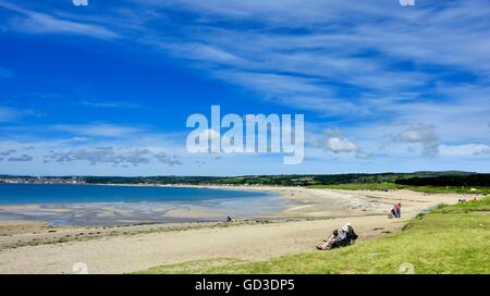 Ein älteres senior Ehepaar sitzt am Strand von Marazion Cornwall England UK Zeitung lesen Stockfoto