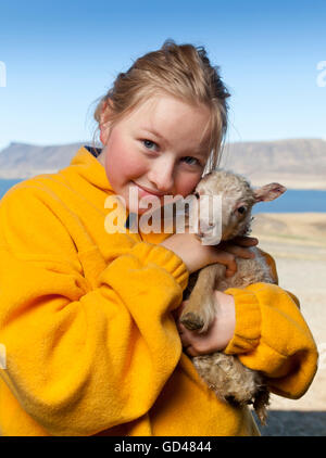 Mädchen hält ein Neugeborenes Lamm, Island Stockfoto