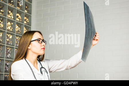 Closeup Portrait des Pflegepersonals intellektuelle Frau mit weißen Laborkittel, Ganzkörper Röntgen Röntgenbild, Ct-Scan, mri, Krankenhaus Klinik Hintergrund zu betrachten. Radiologie Stockfoto