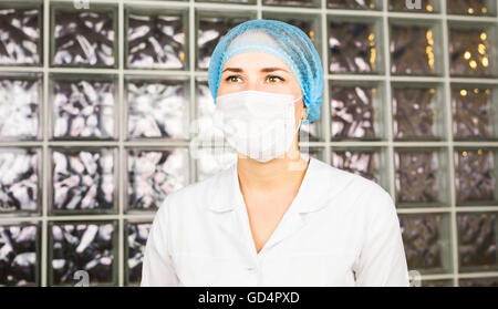 Junge Wissenschaftlerin im OP-Maske schaut aufmerksam in die modernen Labor Stockfoto