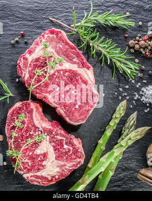 Rib-Eye Steak mit Gewürzen auf dem schwarzen Hintergrund. Stockfoto