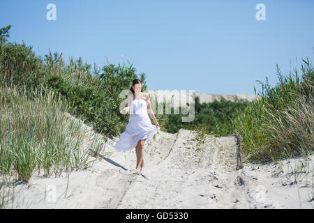 Die schwangere Frau zu Fuß am Strand im Sommer Stockfoto