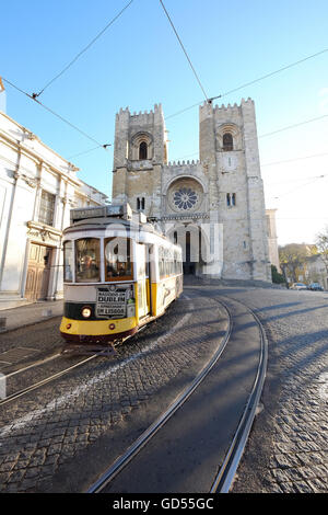 Straßenbahn fahren vor Lissabon Kathedrale gebadet im Sonnenlicht und von hinten beleuchtet durch den Sonnenaufgang am Morgen patriarchalische Kathedrale von St. Mary Major Lisbon Stockfoto