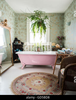 Rosa Doppel endete, roll-Top, freistehende Badewanne im Badezimmer mit Colefax & Fowler print Tapeten und großen vergoldeten Spiegel Stockfoto