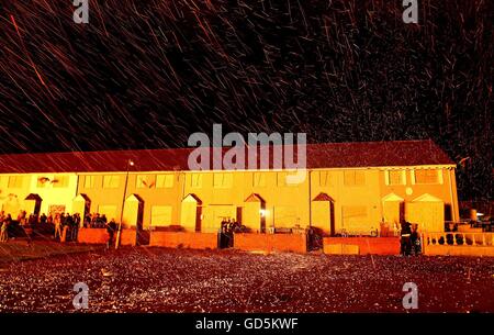 Eine Reihe von Reihenhäusern wird mit Glut übergossen von einem riesigen Lagerfeuer auf der Shankill Road in Belfast wird in der "Elften Nacht" angezündet, um die zwölften gedenkfeiern einzuläuten. Stockfoto