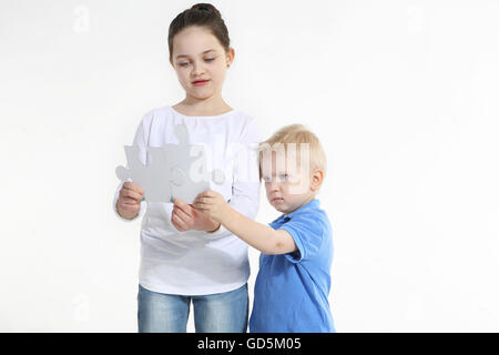 Schwester und Bruder spielen mit Puzzle-Teile isoliert auf weiss Stockfoto