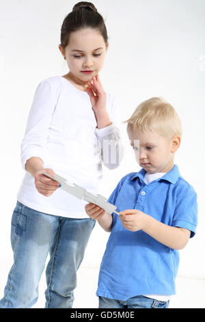 Schwester und Bruder spielen mit Puzzle-Teile isoliert auf weiss Stockfoto