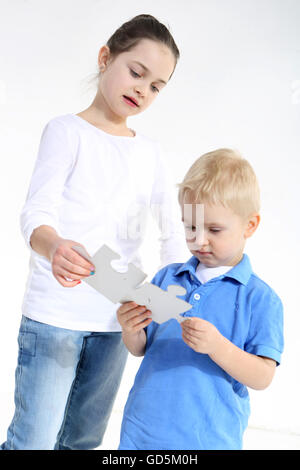 Schwester und Bruder spielen mit Puzzle-Teile isoliert auf weiss Stockfoto