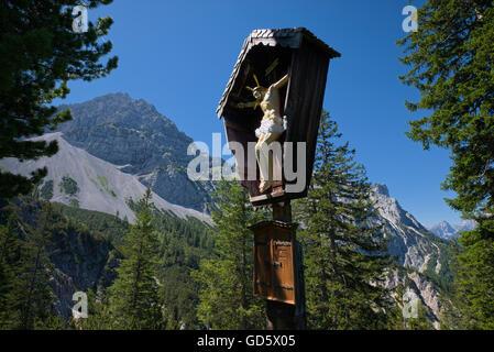 hölzerne Jesus Christus am Kreuz in der Sonne mit Gebirgshintergrund, Karwendel, Deutschland Stockfoto