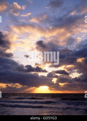 Die untergehende Sonne durch stürmischen Wolken über Meer von Dinas Dinlle Strand Stockfoto