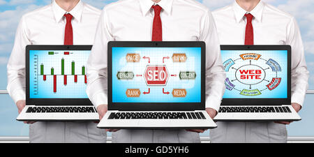 Drei Unternehmer im Büro stehen und Bildschirm Laptop mit Seo-Konzept festhalten Stockfoto