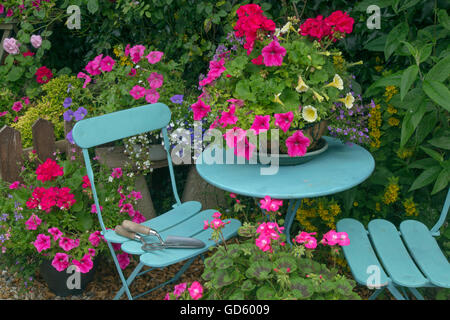 Hübsche Bauerngarten mit Blume Container und blauer Tisch und Stühlen Stockfoto