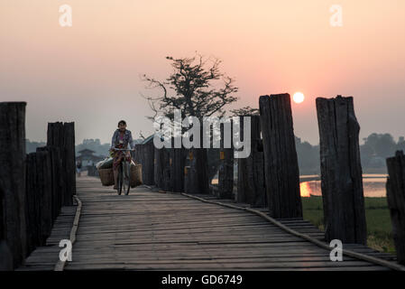Eine Frau mit dem Fahrrad entlang der U Bein Brücke bei Sonnenaufgang, Amarapura, Myanmar. Stockfoto
