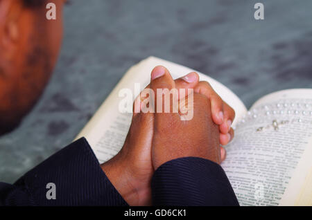 Mann, Falten die Hände betend mit aufgeschlagene Bibel liegen vorne, von hinten Modelle Kopf, Religion Konzept gesehen Stockfoto