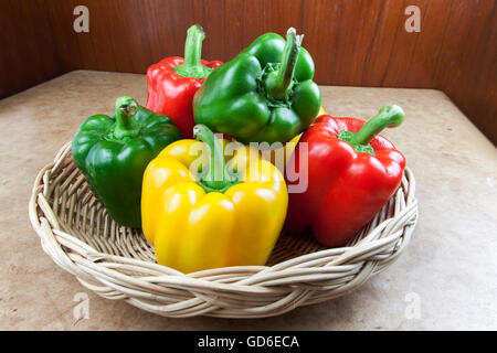 drei Farben Paprika in einem Korb auf dem Tisch Stockfoto