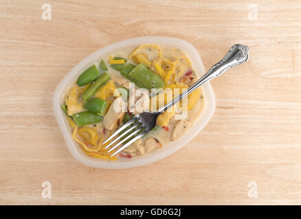 Draufsicht eines Huhns mit Tortellini und Gemüse TV-Dinner in einem Plastikbehälter mit einer Gabel in das Essen auf einem Holztisch. Stockfoto