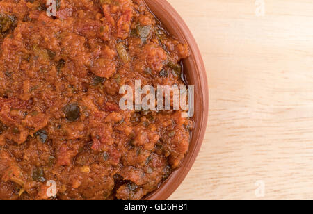 Enge Draufsicht einer kleinen Schüssel gefüllt mit Tomaten-Pesto-Sauce mit getrockneten Tomaten und Pinienkernen auf einem Holztisch. Stockfoto