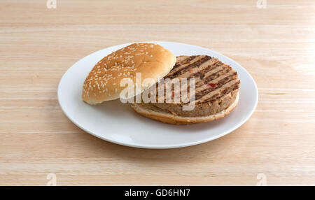 Seitenansicht eines Veggie-Burger in einem Brötchen mit keine Gewürze auf einem Teller auf einer hölzernen Tischplatte. Stockfoto