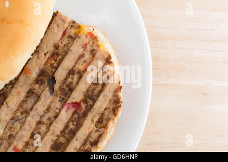 Enge Draufsicht eines Veggie-Burger in einem Brötchen mit keine Gewürze auf einem Teller auf einer hölzernen Tischplatte. Stockfoto