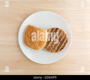 Draufsicht eines Veggie-Burger in einem Brötchen mit keine Gewürze auf einem Teller auf einer hölzernen Tischplatte. Stockfoto