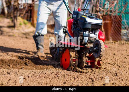 Mann im Garten arbeiten mit Garten Lenkstange. Garten Lenkstange zu arbeiten, Nahaufnahme. Mann mit Traktor Pflege Feld an der Feder Stockfoto