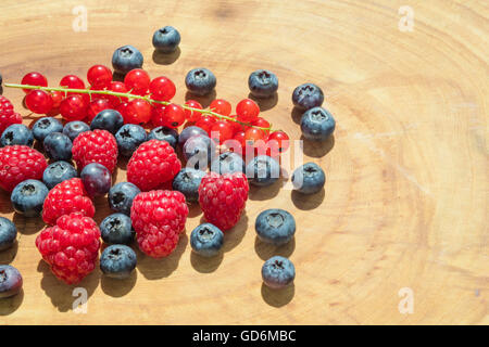 Gruppe von Himbeeren, Heidelbeeren und roten Johannisbeeren auf ein Holzbrett gelegt. Stockfoto