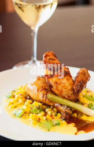 halbe Mary Freilandhaltung Huhn über Succotash mit einem Glas Chardonnay Wein, Nuance Restaurant, Santa Barbara, Kalifornien Stockfoto