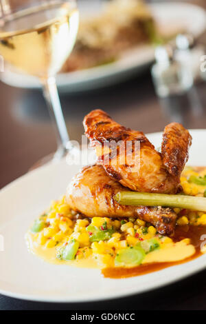 halbe Mary Freilandhaltung Huhn über Succotash mit einem Glas Chardonnay Wein, Nuance Restaurant, Santa Barbara, Kalifornien Stockfoto