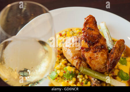 halbe Mary Freilandhaltung Huhn über Succotash mit einem Glas Chardonnay Wein, Nuance Restaurant, Santa Barbara, Kalifornien Stockfoto