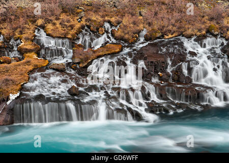 Wasser fließt aus einem großen Lavafeld in den Fluss am Hraunfossar, Island. Stockfoto