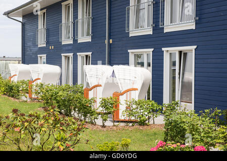 schöner Garten mit weißen Strandkörben und blaues Haus Stockfoto