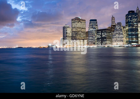 Blick auf Manhattans Financial District in der Abenddämmerung von der Brooklyn Bridge Park, New York City, NY Stockfoto