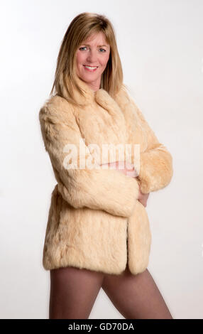 Mittlere gealterte Frau mit verschränkten Armen trägt einen kurzes Fell Mantel Stockfoto