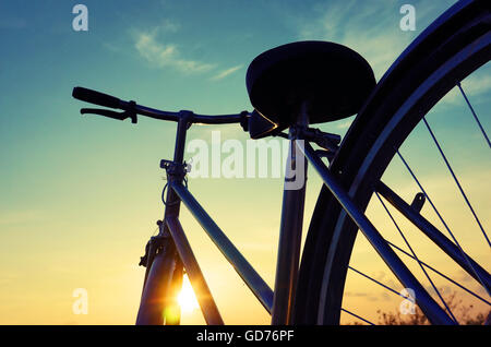 Schöne Nahaufnahme Szene des Fahrrades bei Sonnenuntergang, Sonne am blauen Himmel mit Vintage Farben Silhouette des Rad nach vorne zur Sonne Stockfoto