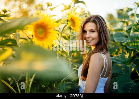 Schöne glückliche Frau umgeben von Sonnenblumen Stockfoto