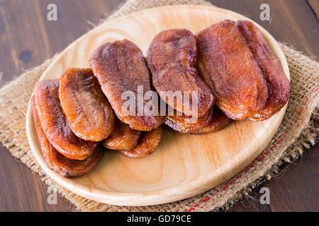 Getrocknete Bananendessert Thailand auf einer Platte aus Holz und Tuch Säcke auf dem Holzboden angeordnet. Stockfoto