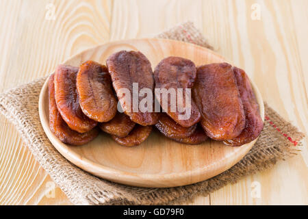 Getrocknete Bananendessert Thailand auf einer Platte aus Holz und Tuch Säcke auf dem Holzboden angeordnet. Stockfoto