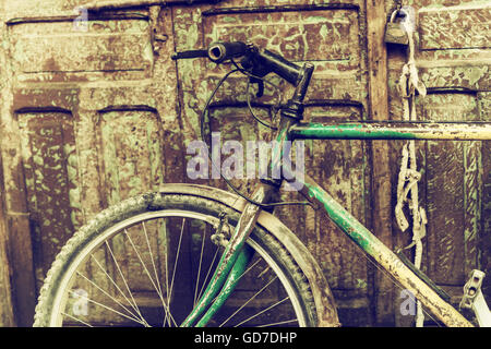 Altes Fahrrad gegen rostigen Holztür. Stockfoto