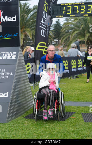 Reifer Mann Zieleinlauf der Kiama Coastal Classic laufen beim Druck einer Frau in einem Rollstuhl, Kiama, New-South.Wales, Australien Stockfoto