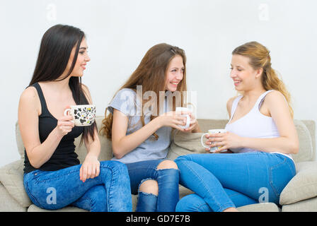 Drei glückliche Freunde reden und trinken Kaffee oder Tee Stockfoto