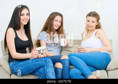 Drei glückliche Freunde reden und trinken Kaffee oder Tee Stockfoto